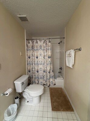 Une salle de bain équipée de toilettes, d’une douche et d’un porte-serviettes.