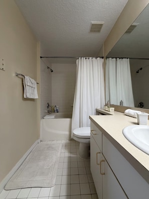 A bathroom with a bathtub, toilet, sink, and a mirror.