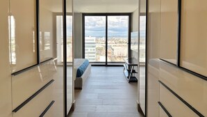 Una habitación de hotel moderna con un gran ventanal corredero que da a un balcón con vistas a la ciudad.