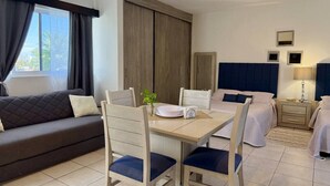 Ein Hotelzimmer mit Sofa, Esstisch mit Stühlen, Bett, Nachttisch und Lampe.