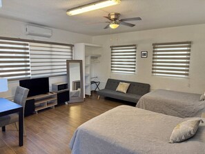 Quarto moderno com duas camas, um sofá, uma TV e um ventilador de teto.