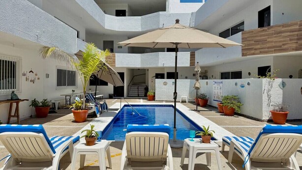 A pool area with lounge chairs, a pool, and potted plants.