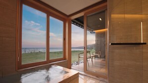 Un baño moderno con un ventanal grande, una bañera y vistas al exterior.