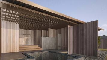 Un edificio moderno con fachada de madera, un espacio al aire libre cubierto y una fuente de agua de piedra.