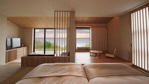 Un dormitorio moderno con una cama grande, televisión y vista al océano.