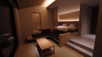 A modern hotel room with a sofa, a wooden table, and a bed with a headboard.
