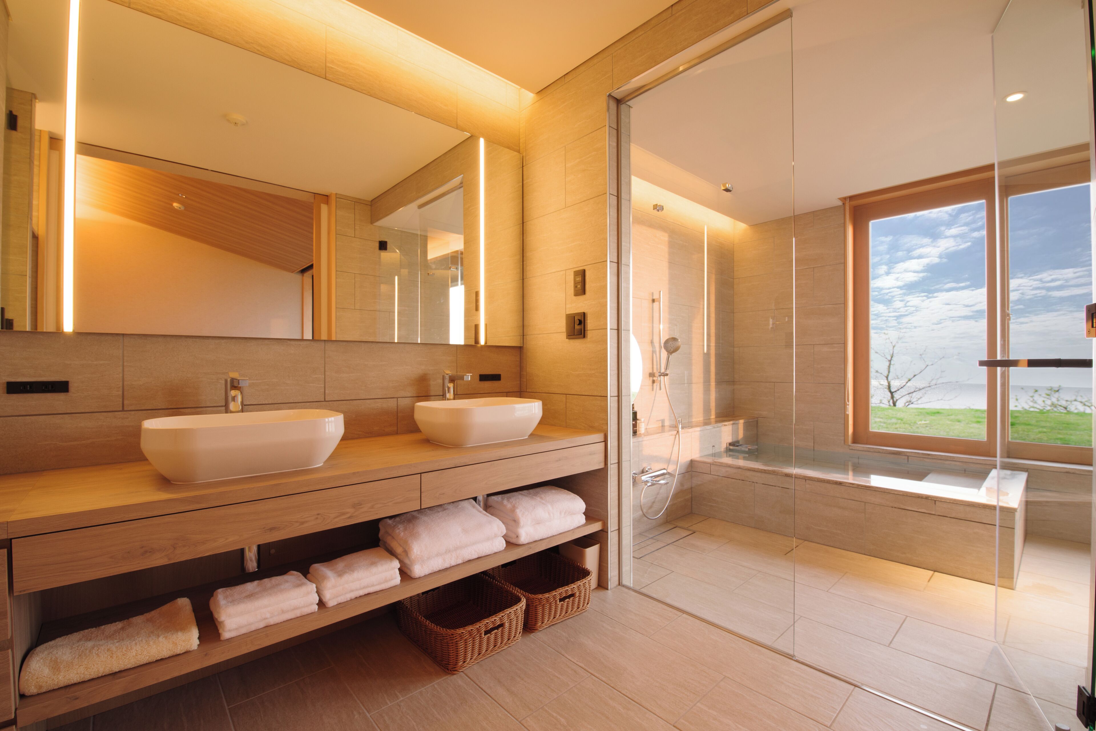 Un baño moderno con dos lavamanos, un espejo grande y una bañera.