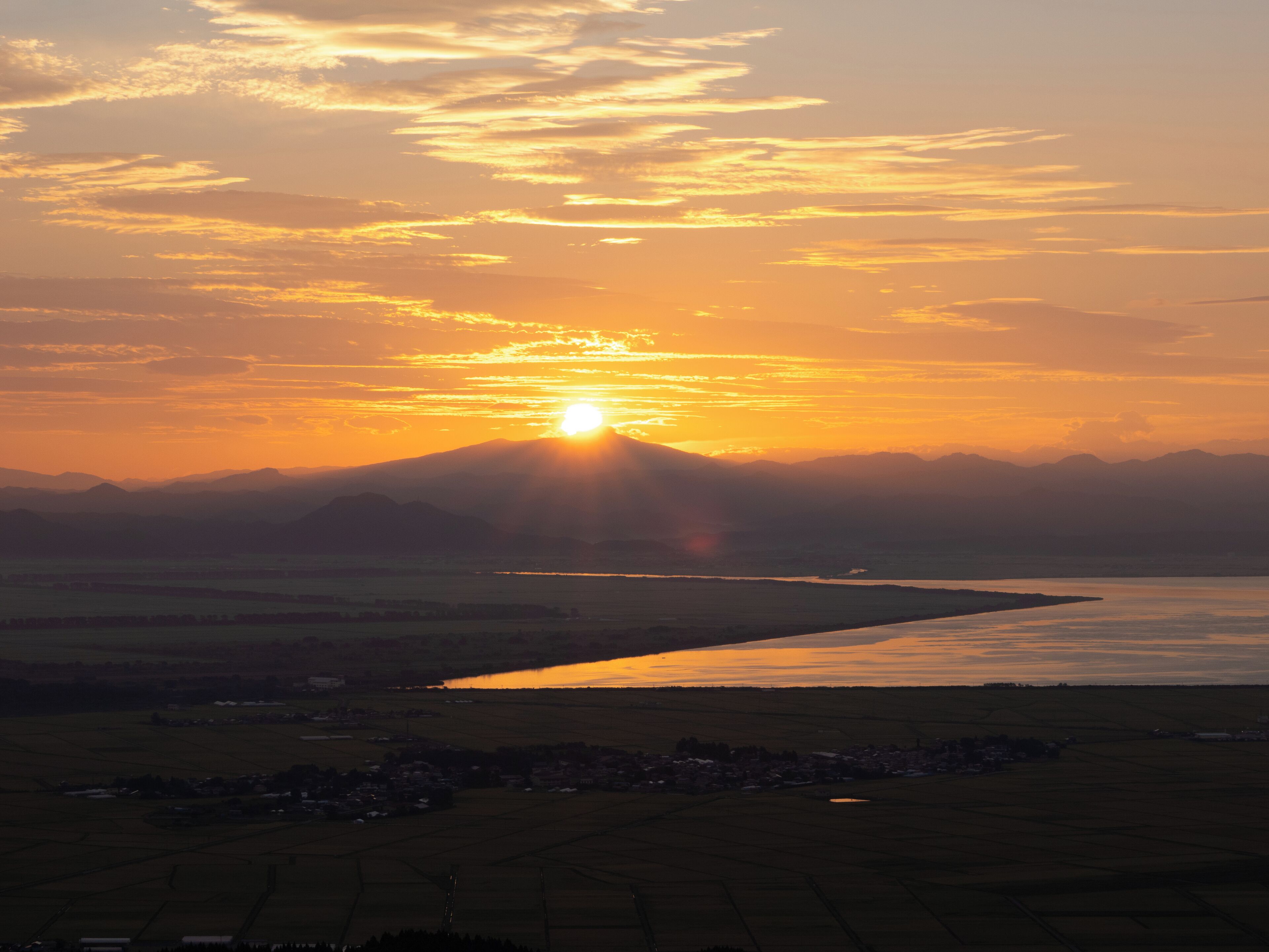 Un atardecer sobre un río con montañas al fondo.