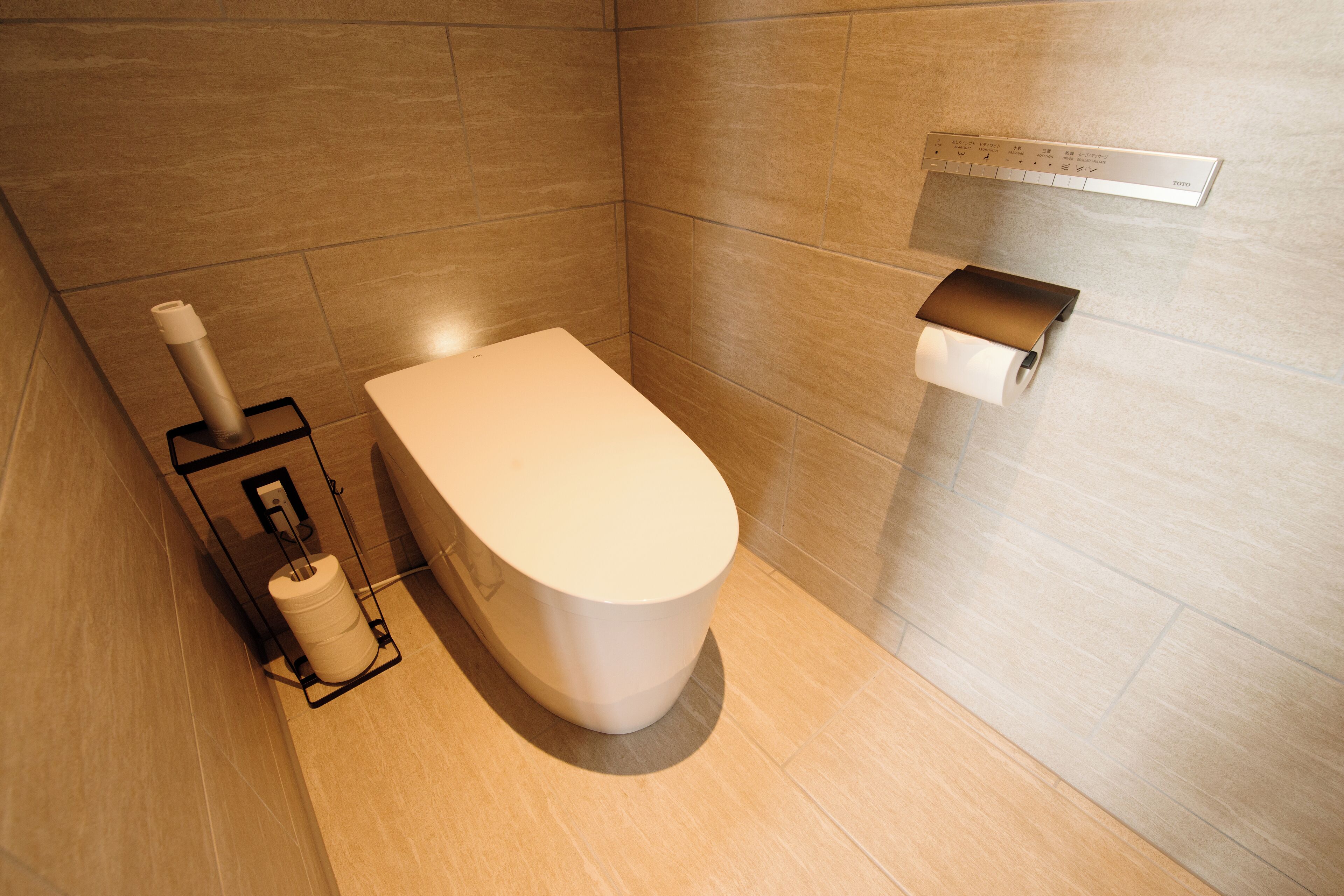 A modern bathroom with a toilet, a bidet, and a toilet paper holder on the wall.