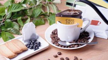 A white cup with a coffee drink, a tea bag, and a spoon on a saucer.