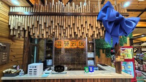 A hotel reception desk with a bamboo wall, a blue bow decoration, and a cash register.