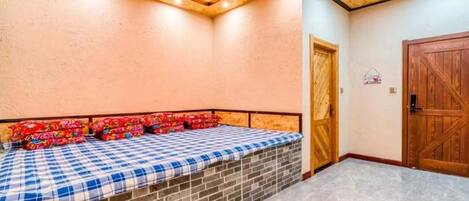 Una habitación con una cama, una puerta de madera y suelo de baldosas.