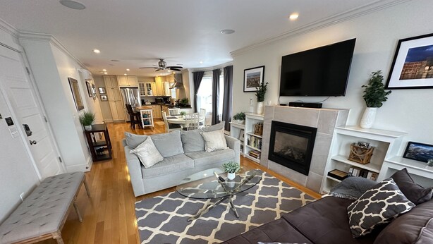 A modern living room with a grey sofa, a brown sofa, a glass coffee table, and a fireplace. - 86 Dr Marcus House - Popular Broadway Area (Newport)