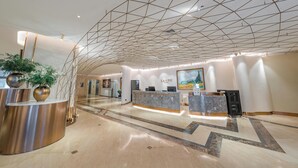 A modern hotel lobby with a geometric ceiling design, a reception desk, and a large painting on the wall. - Shanghai Lujiazui BaBaiBan LANOU Hotel (Shanghai)