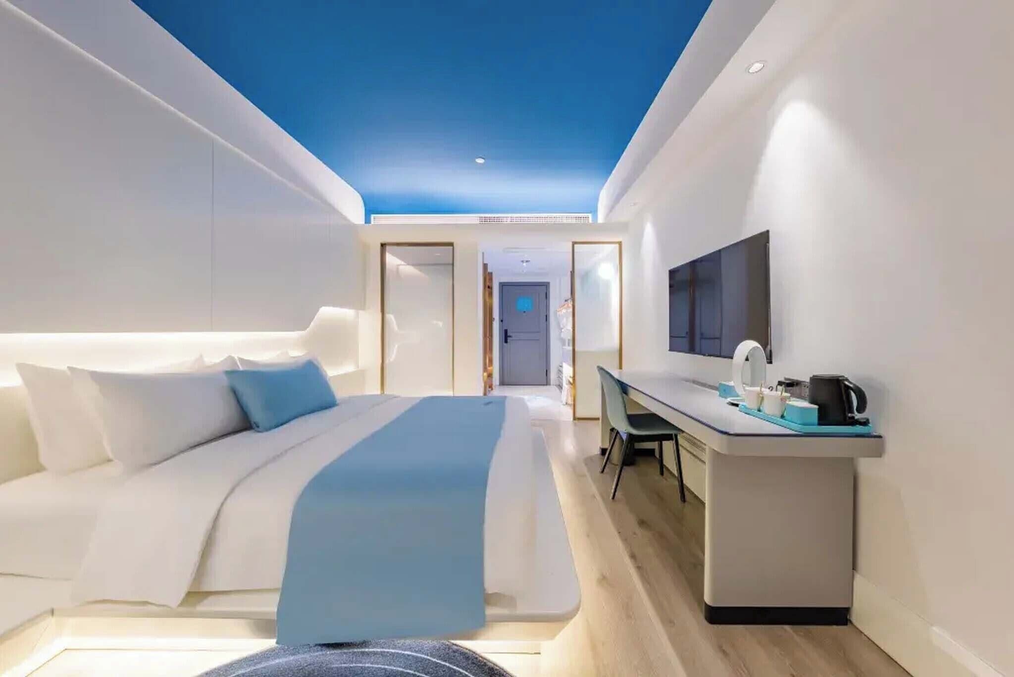 A modern hotel room with a bed, desk, and TV.