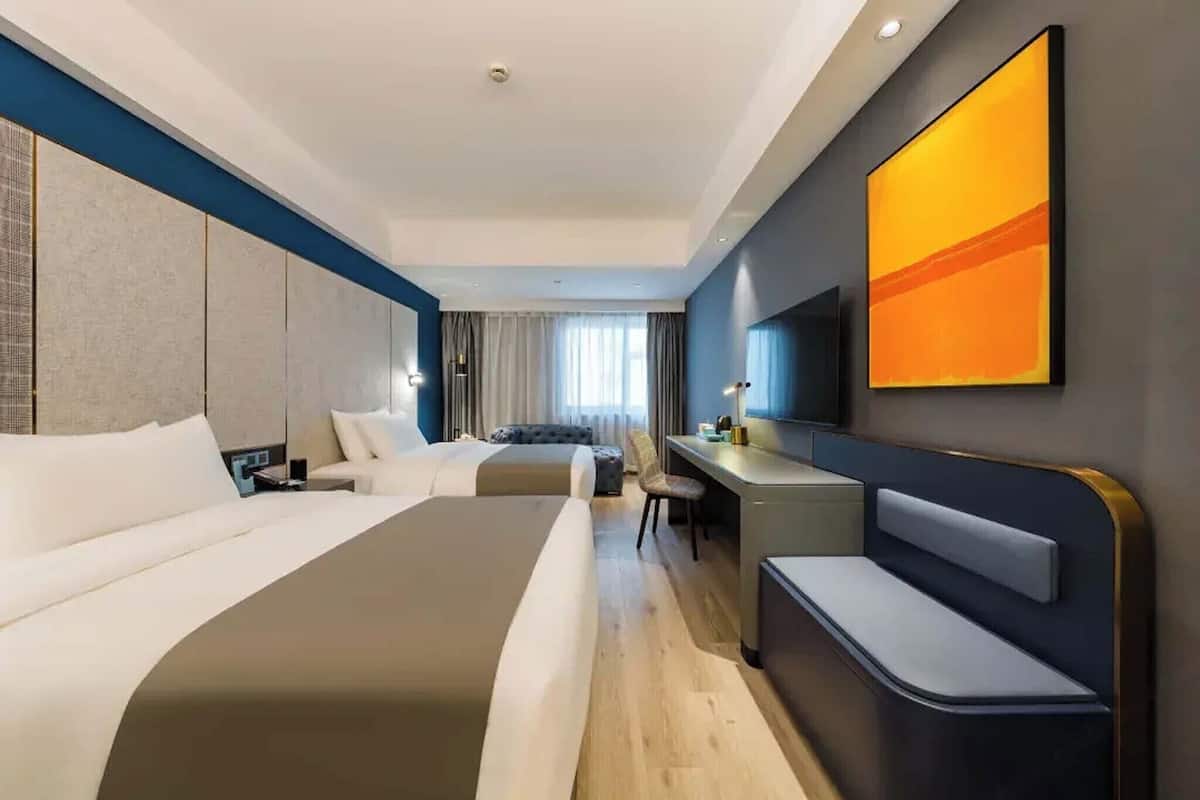 A modern hotel room with a large bed, a desk, and a television.