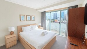 A hotel room with a large bed, a TV, a desk, and a balcony with a city view. - Queen Studio | Beach and Tram at Doorstep @ Legend (Surfers Paradise)