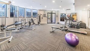 A gym with exercise equipment, a purple exercise ball, and large windows. - Queen Studio | Beach and Tram at Doorstep @ Legend (Surfers Paradise)