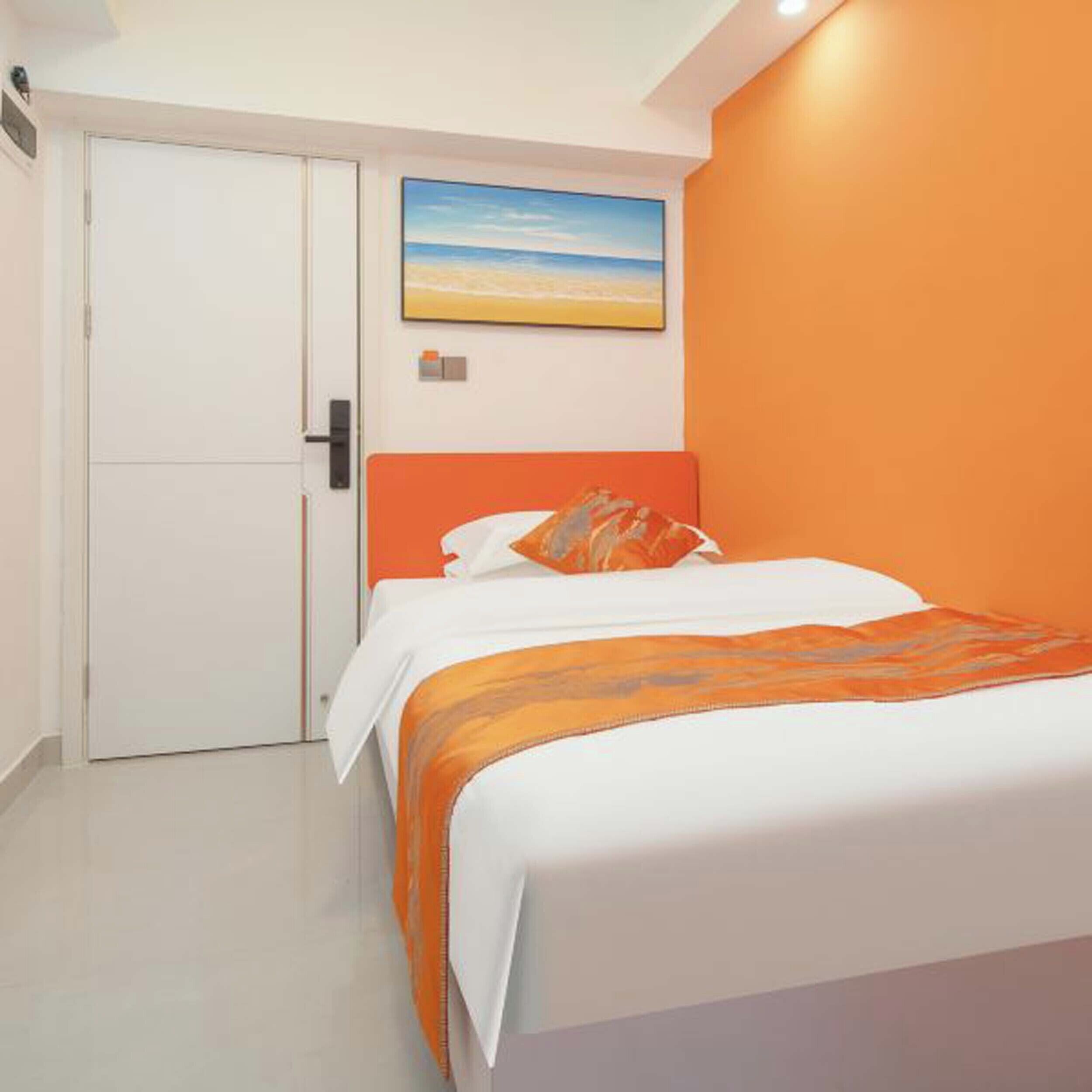 A bedroom with a bed, a door, and a painting on the wall.