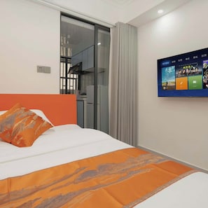 A hotel room with a bed, a TV mounted on the wall, and a sliding door leading to a balcony. - Chengxing Hotel Apartment (Shenzhen)