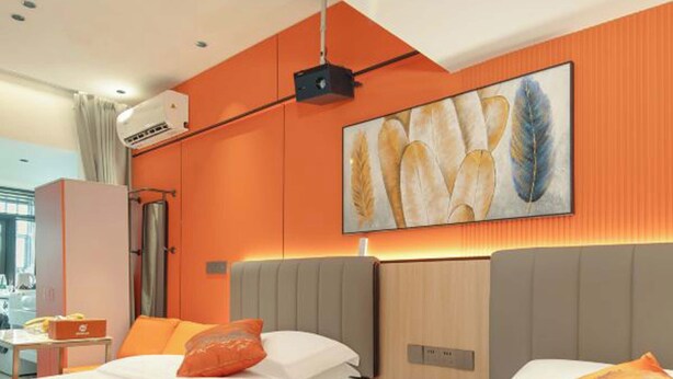 A hotel room with two beds, orange bedding, a large window, and a painting of wheat on the wall. - Chengxing Hotel Apartment (Shenzhen)