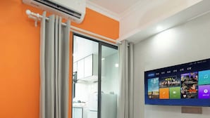 A modern living room with a sofa, a small table, and a TV mounted on the wall displaying various apps. - Chengxing Hotel Apartment (Shenzhen)