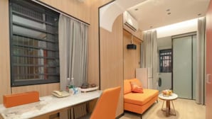 A modern hotel room with a desk, orange chair, sofa, and a small round table. - Chengxing Hotel Apartment (Shenzhen)