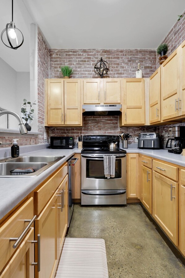 A kitchen with wooden cabinets, a stainless steel stove, a microwave, and a sink. -     Spotless Luxury Retreat. Walk to Food & Fun. King Bed. Free Parking (Chattanooga)