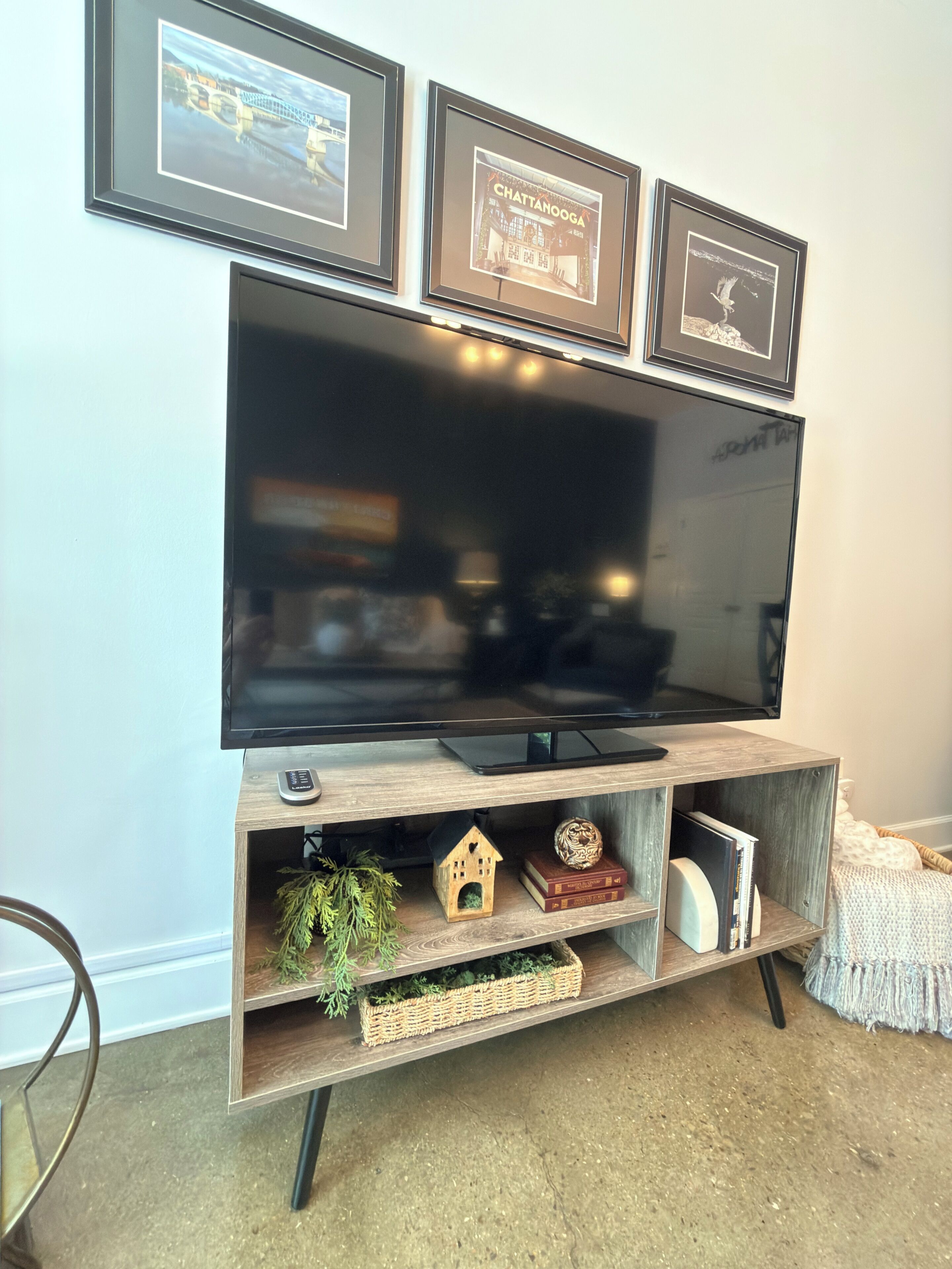 A flat-screen TV mounted on a wooden entertainment center with shelves below.