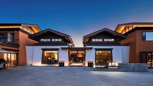 A modern hotel entrance with a symmetrical facade, large windows, and a stone pathway leading to the entrance.