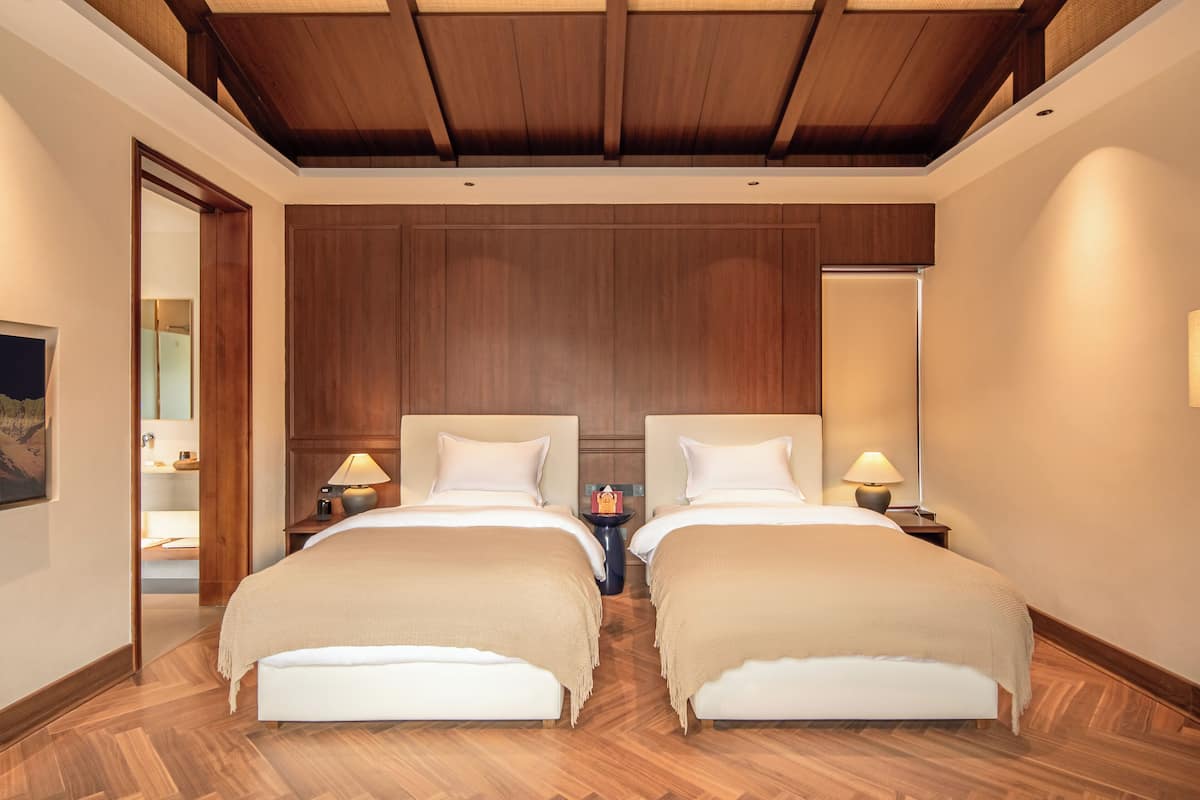 A hotel room with two beds, wooden paneling on the walls, and a wooden ceiling.