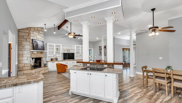 A spacious kitchen with a central island, white cabinetry, and a stone accent wall.
