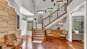 A spacious living area with a stone accent wall, a wooden staircase, and a cozy seating area.