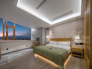 A modern hotel room with a skylight, a large bed, a nightstand, a desk, and a view of the cityscape.