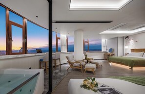 A modern hotel room with a city view, a large bed, a sitting area with a table and chairs, and a bathtub. - Bohan Shenhua Riverside Resort Hotel (Xishuangbanna Dai)