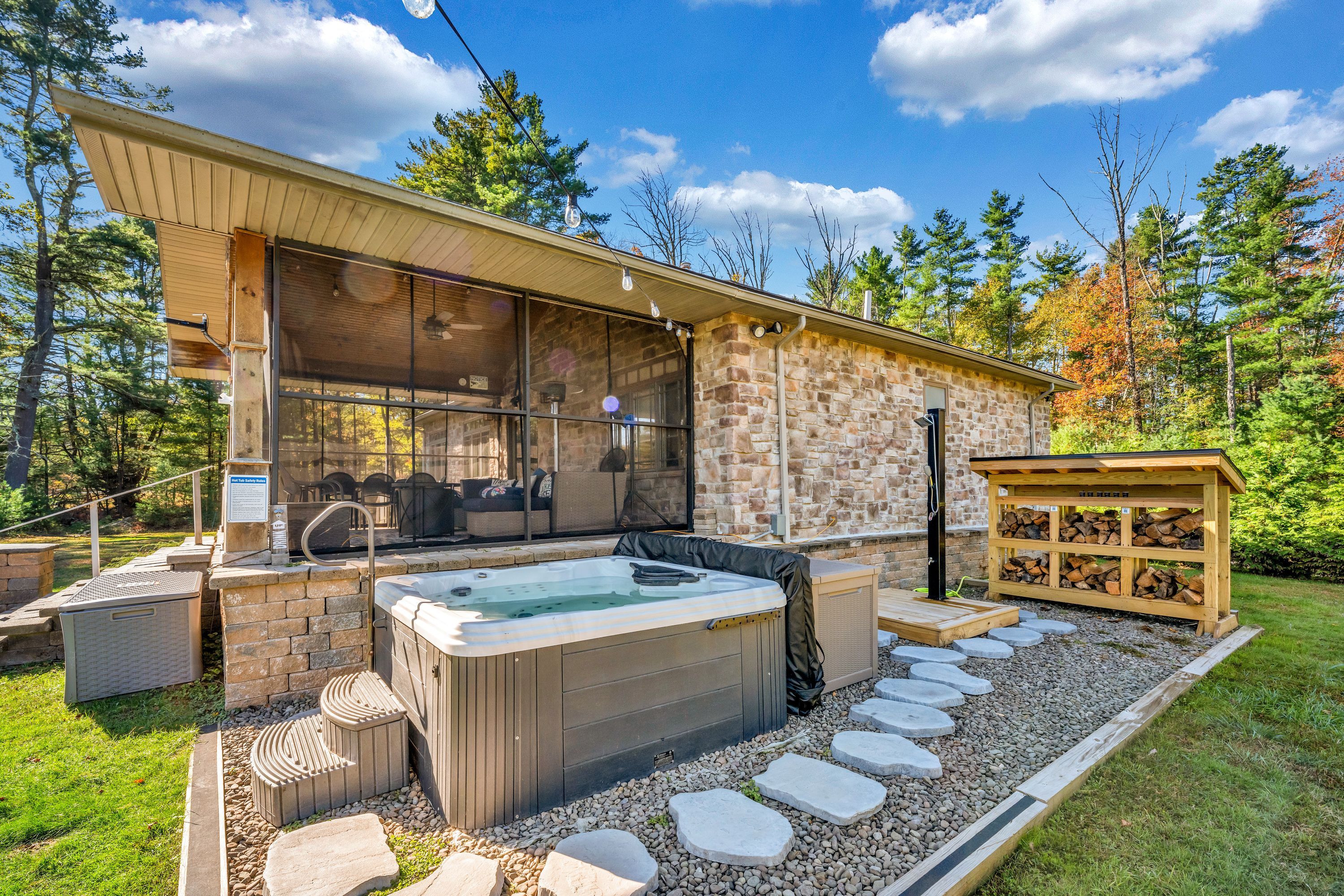 A modern outdoor hot tub area with stone walls and a wooden deck.