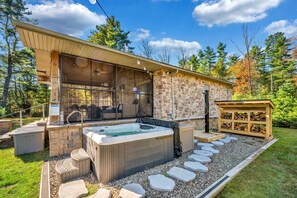 A modern outdoor hot tub area with stone walls and a wooden deck. - 2 Lake Cabins Pool+hottub Game Room 23acs (Highland Lake)
