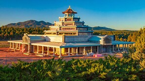 A multi-tiered pagoda-style building with a central tower, surrounded by a covered walkway and open areas.