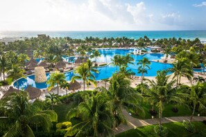 Ein Resort mit mehreren Pools, umgeben von Palmen und Blick auf den Strand.