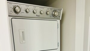 A stacked washer and dryer unit with control knobs and a door handle.