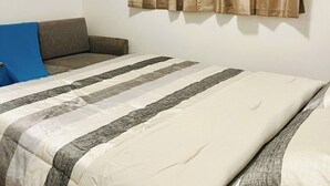 A bedroom with a bed, a sofa, and curtains.