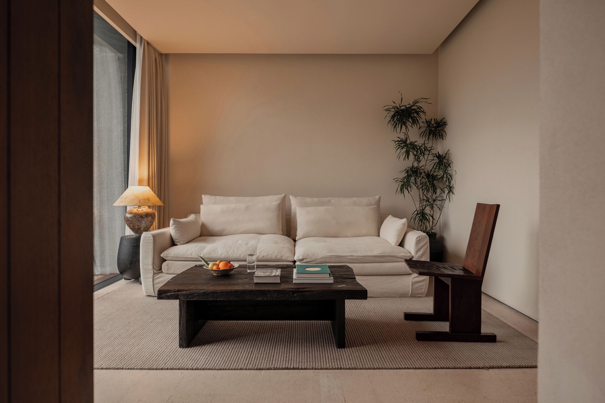 En moderne stue med sofa, sofabord, lampe og en potteplante.