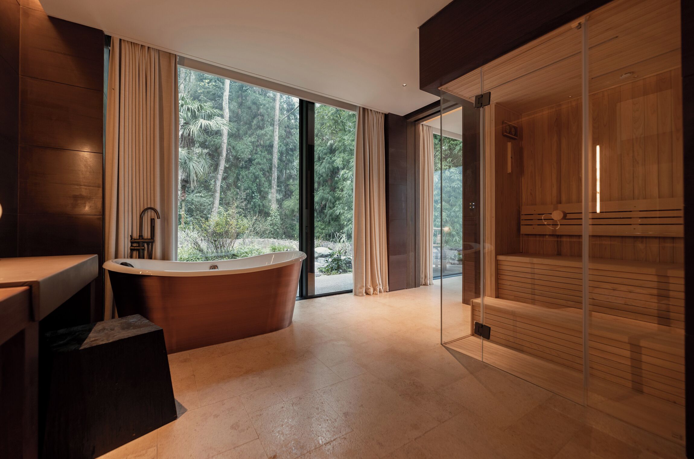 A modern bathroom with a freestanding bathtub, large windows, and a glass shower enclosure.