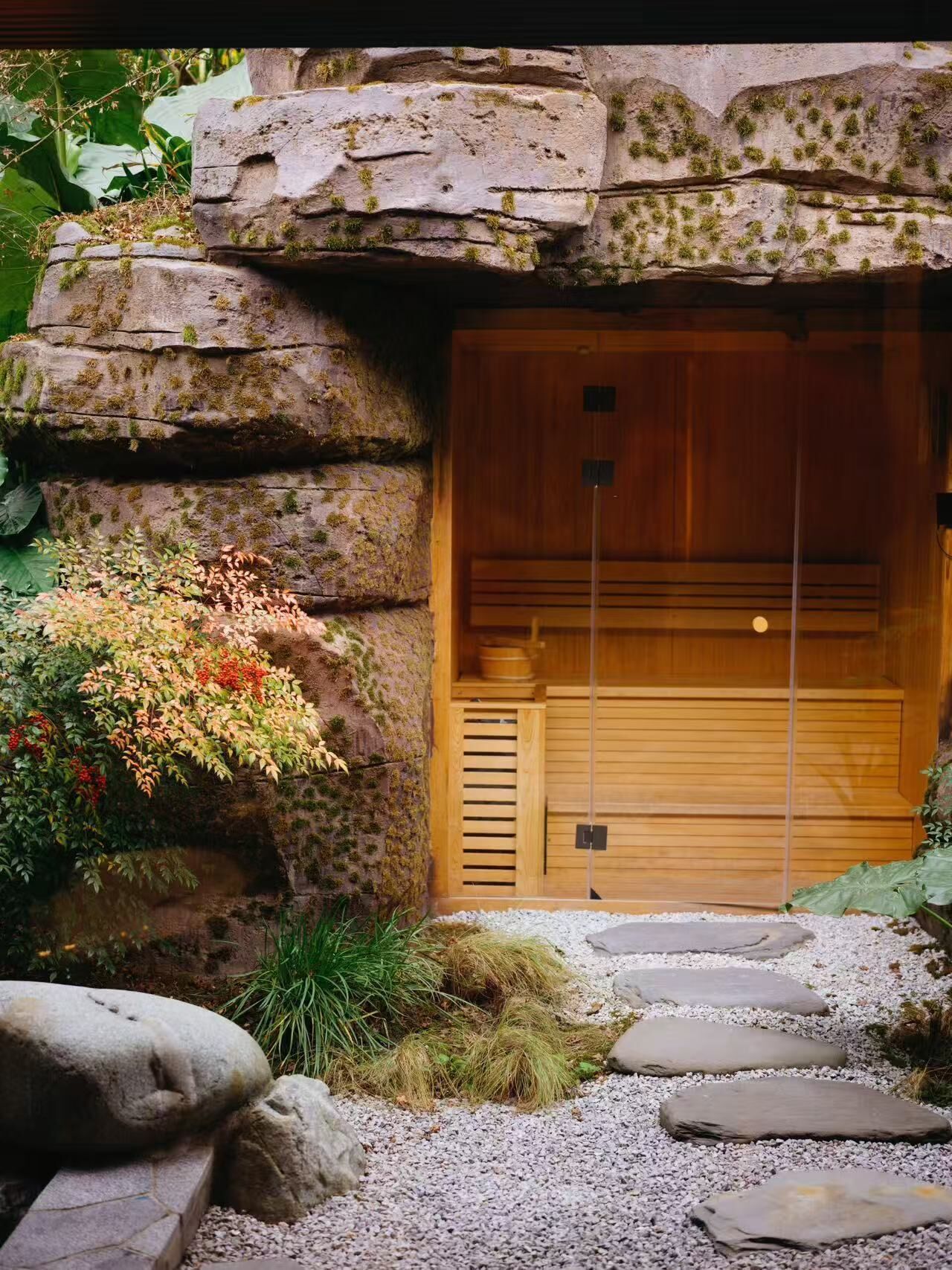 Entrada a una sauna de madera tradicional con puerta de madera y un pequeño banco interior.