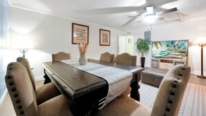 A dining area with a wooden table, beige chairs, and a ceiling fan. - Cozy 2-bedroom apartment in centrally located Deltona. SLEEPS 7 PEOPLE! (Deltona)
