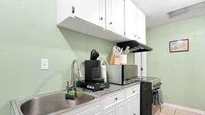 A kitchen with white cabinets, a stainless steel sink, a coffee maker, and a microwave. - Cozy 2-bedroom apartment in centrally located Deltona. SLEEPS 7 PEOPLE! (Deltona)