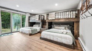A modern bedroom with two beds, a balcony, and a large window.