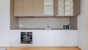 A compact kitchen with a built-in oven, a sink, and cabinets above. - Blueground | Kirchberg, balcony, nr Parc de Merl (Luxembourg)