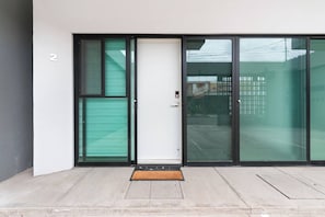 A modern building entrance with a sliding glass door, a white door, and a number '2' sign.