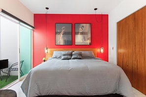 A bedroom with a bed, two wall-mounted picture frames, a sliding glass door, and a wooden panel wall.